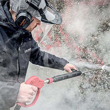 Person som spyler bort tagging med Clena Høytrykksspyler